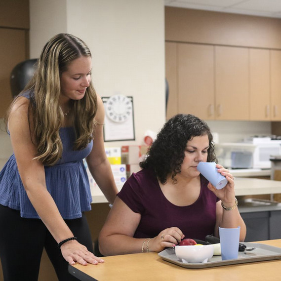 SLP student helping client drink water out of a cup