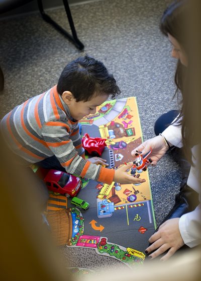 Speech-language pathologist sitting with child client  playing with a toy airplane