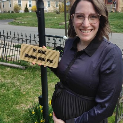 Brianna Brim holding a sign that says "PH, done, Brianna Brim, PhD"