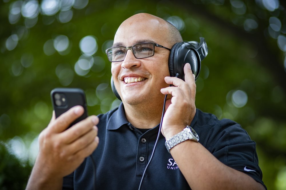 Man with over the ear headphones holding a iPhone