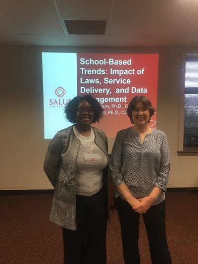 Carrie Knight  and coworker standing in front of a presentation