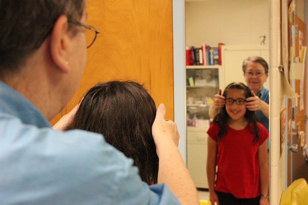 student trying on glasses