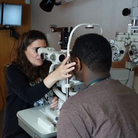 Dr. giving eye exam to school kid