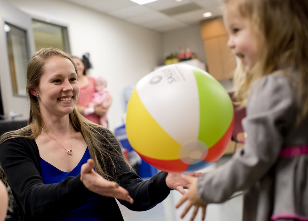 OT students playing with a beach ball with a pediatric client