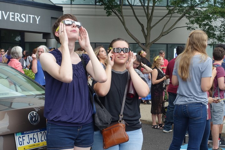 Two students looking up at the solar eclipse with eclipse glasses