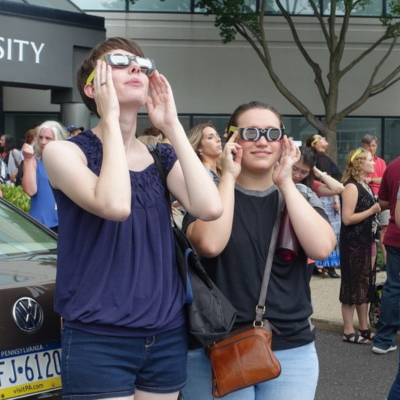 Two students looking up at the solar eclipse with eclipse glasses