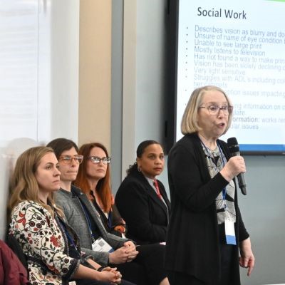 Women speaking in a conference room to other people