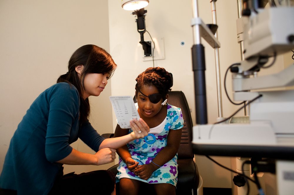 young girl with eye patch talking to an optometrist