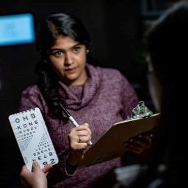 Patient reading hand held eye chart