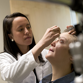 Optometrist putting eyedrops in patient's eye