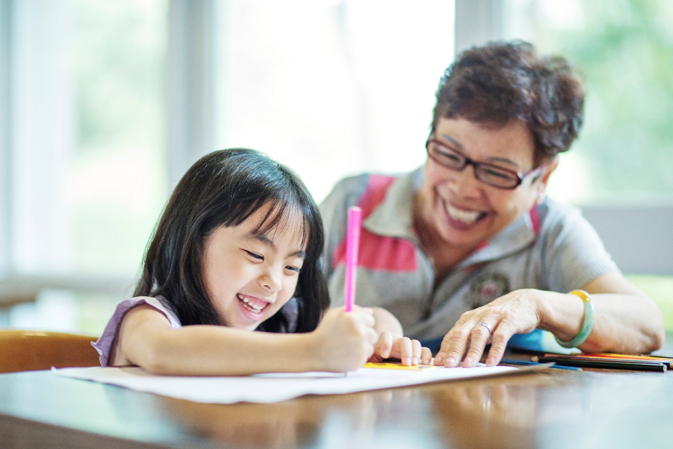 young girl writing with mom