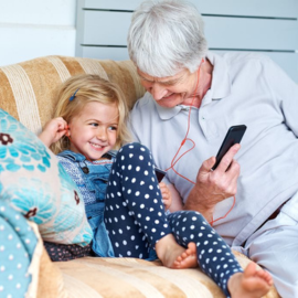 grandfather and granddaughter using headphones together