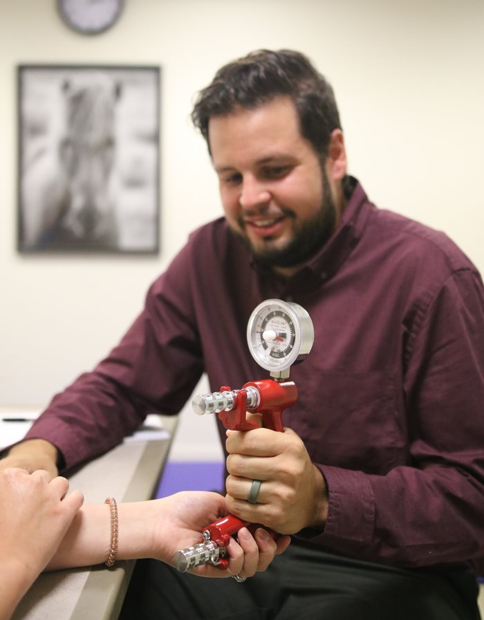 man working with a hand strength measuring device