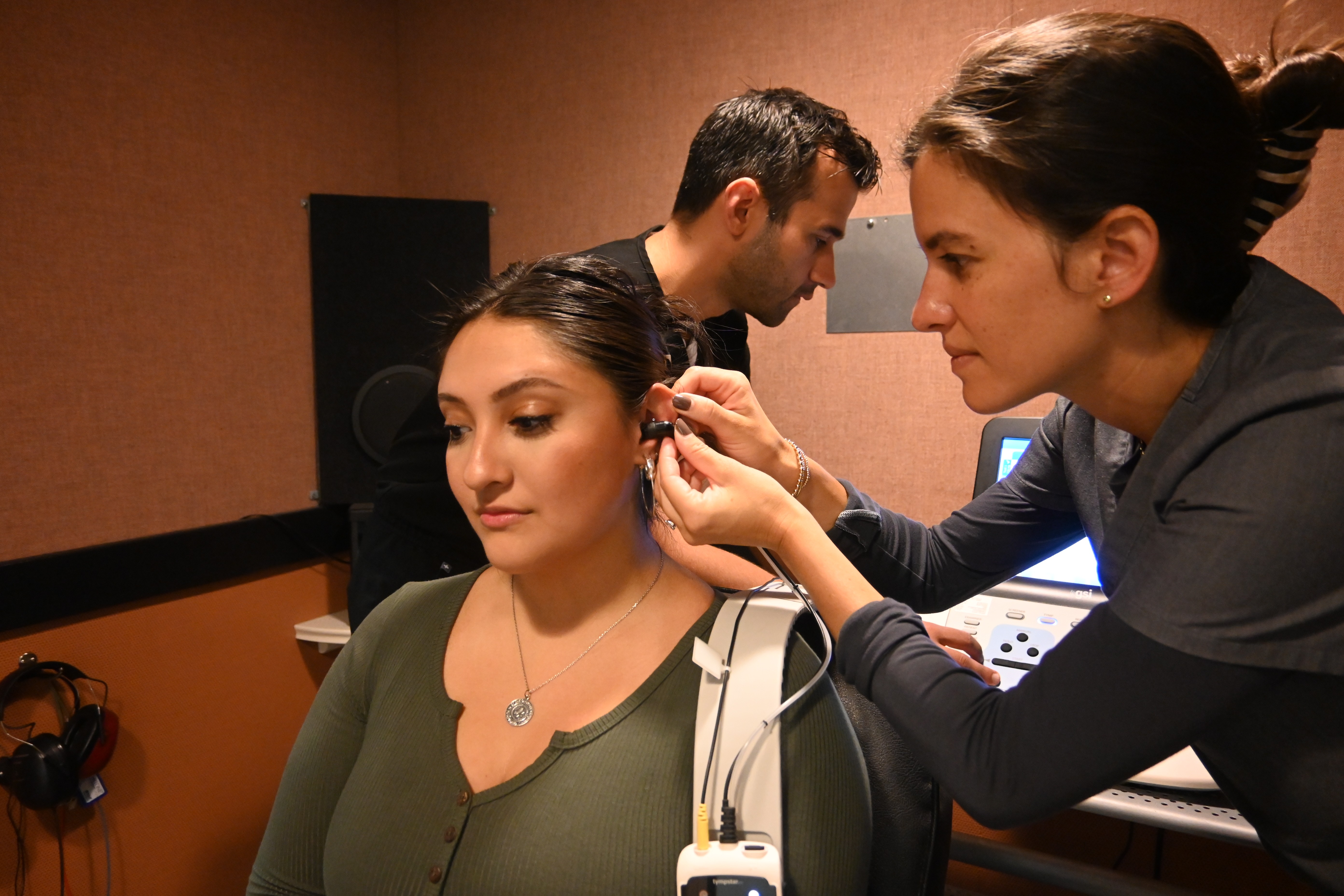 Student and faculty examine patient in hearing lab