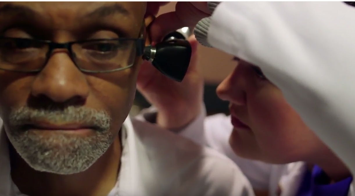 Audiologist look inside elderly patients ear during an exam