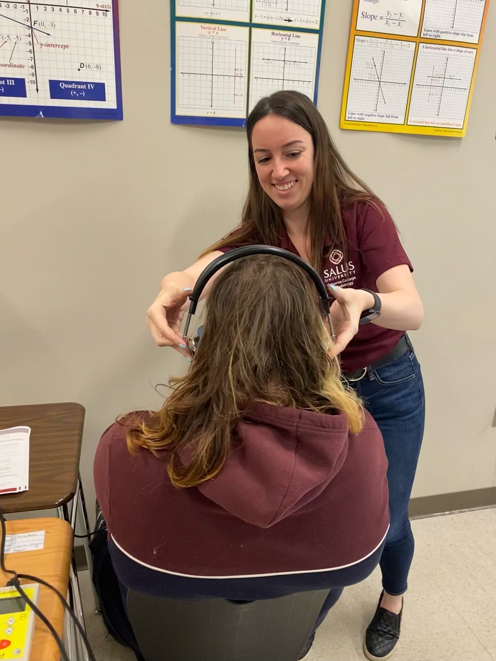 audiology student putting headphones on high schooler