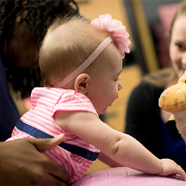 Baby and student playing with a stuffed animal sheep