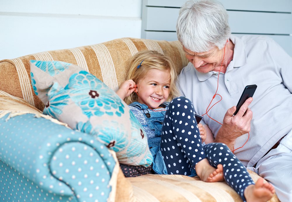 grandfather and granddaughter using headphones together