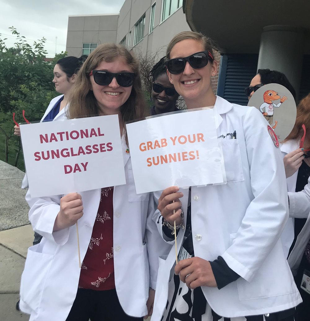 Students wearing sunglasses and holding "National sunglasses day" signs