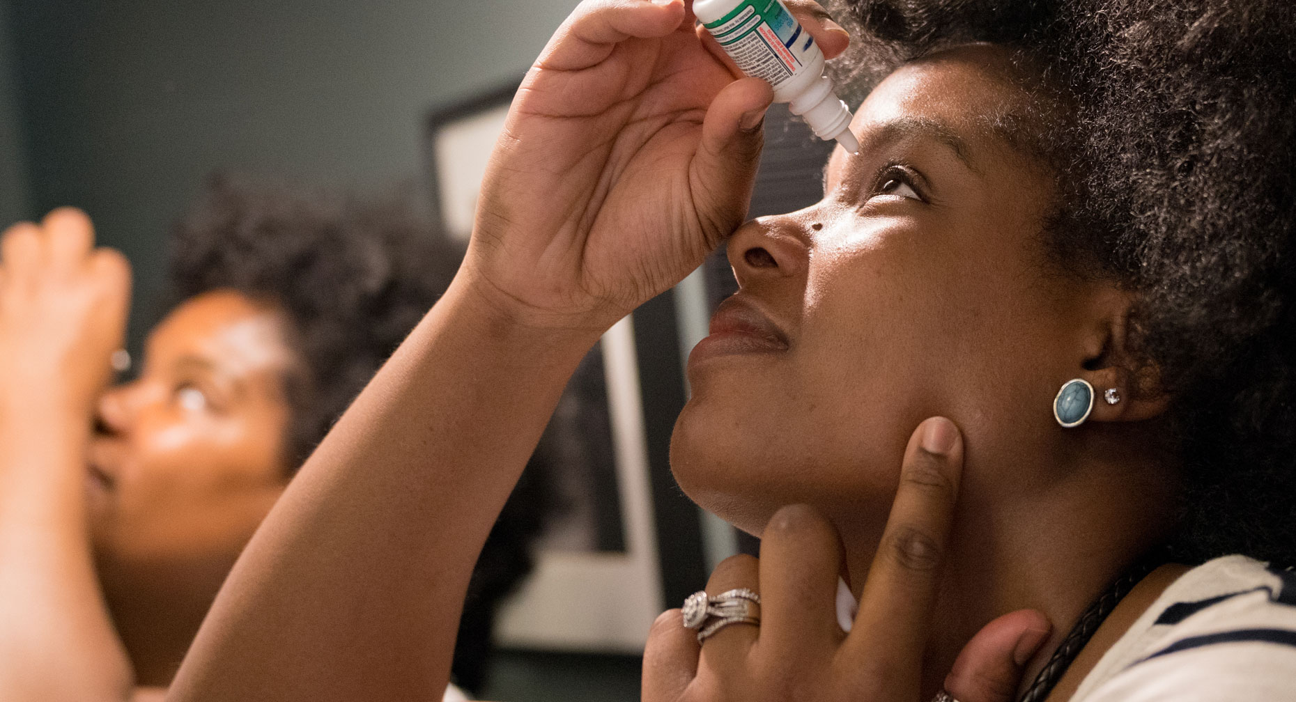 Black woman using eye drops for her eye