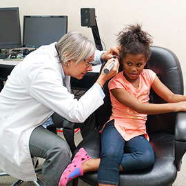 Dr. Owen giving an ear exam to a pediatric patient