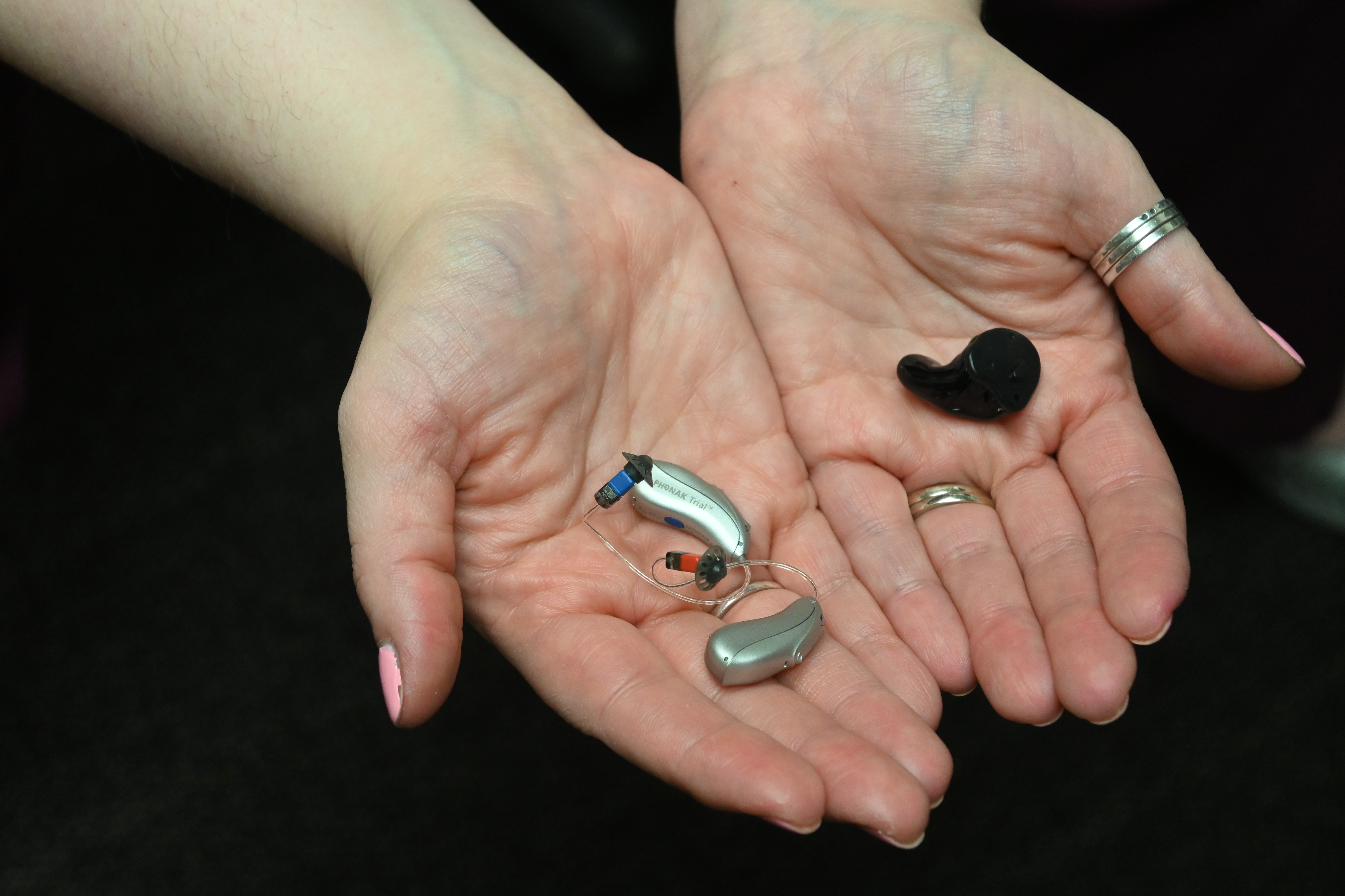 Hands holding a pair of hearing aids