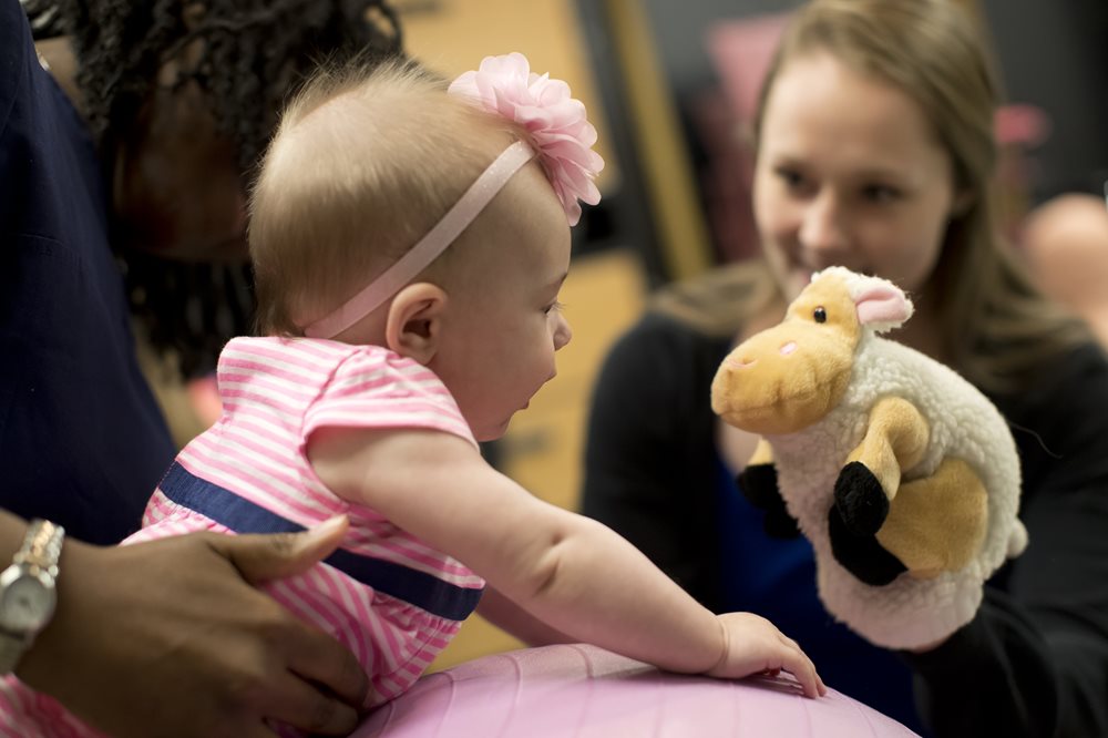 Baby and student playing with a stuffed animal sheep