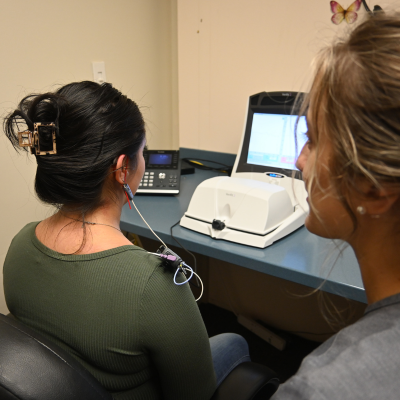 Woman sitting with a listening device in ear