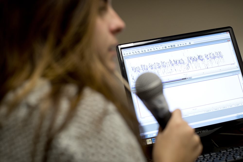 Woman holding microphone for a voice exam at SLI